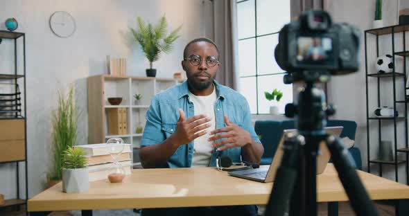 African Blogger in Glasses Filming New Video for His Audience with Professional Videocamera on Home