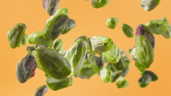 Flying of Peeled Pistachios in Pale Orange Background