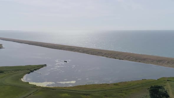 Aerial rotating and tracking from right to left above the fleet lagoon near the Abbotsbury Swannery,