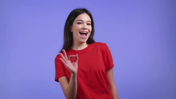 Pretty Asian Woman Showing Ok Okay Sign Over Violet Studio Background