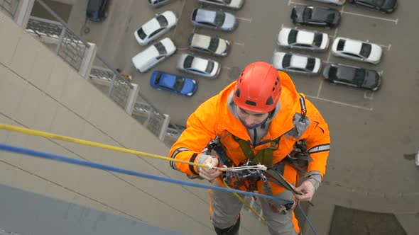 Industrial Climber in Suit Sets Up Protector Protect Against Abrasion of Rope When Descending From