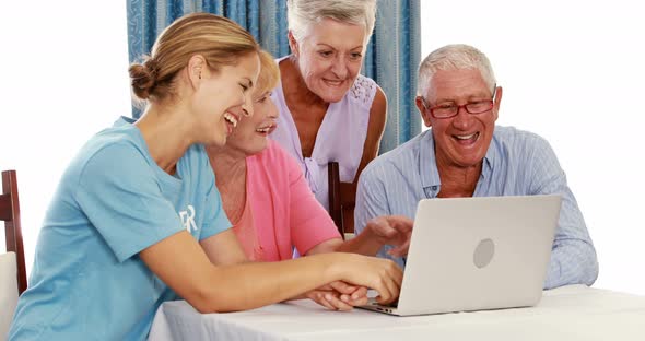 Female volunteer and senior citizens using laptop