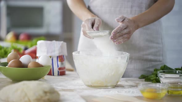 Closeup of Woman Hands Sieving Flour Over the Glass Bowl With Dough, Bakery