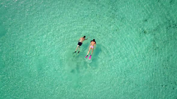 Aerial view of man and woman swimming in masks and flippers in turquoise water.