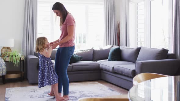 Caucasian mother and daughter having fun dancing in living room