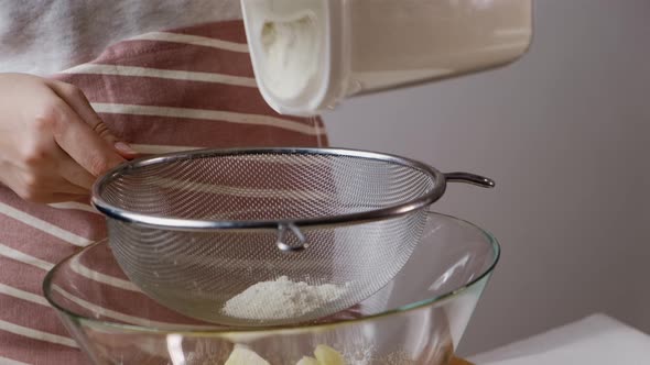 Lady Pours Flour Through Sieve Over Bowl for Baking