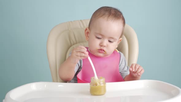 Baby eats vegetable puree on his own while sitting on a feeding chair