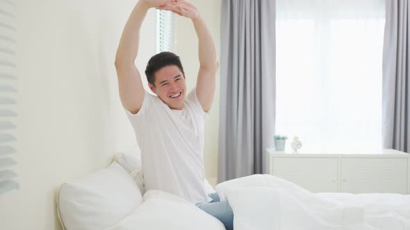 Asian handsome male in pajamas wake up in the morning with happiness.