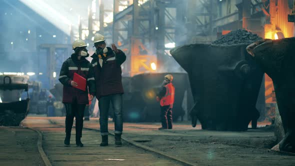 Steel Workers are Walking Along the Premises of the Factory