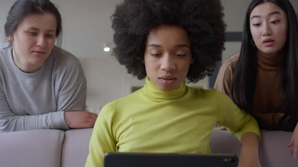 Portrait of Absorbed African American Young Woman Messaging Online on Tablet with Bored Caucasian