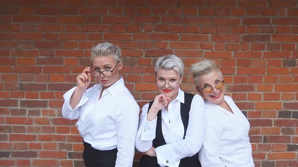 Three Caucasian Blondes Businesswomen Pose Against Brick Wall