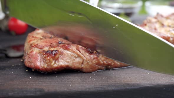 Female Hands Cut Juicy Grilled Steak on a Wooden Table