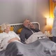 Pensive Sick Senior Man Laying on Bed with Glass of Water Nurse Take Care of Elderly Couple at Home - VideoHive Item for Sale