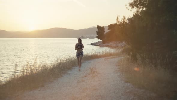 Athletic Caucasian Girl Jogging By the Sea at Sunset