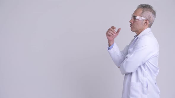 Profile View of Happy Persian Man Doctor Wearing Protective Glasses Thinking