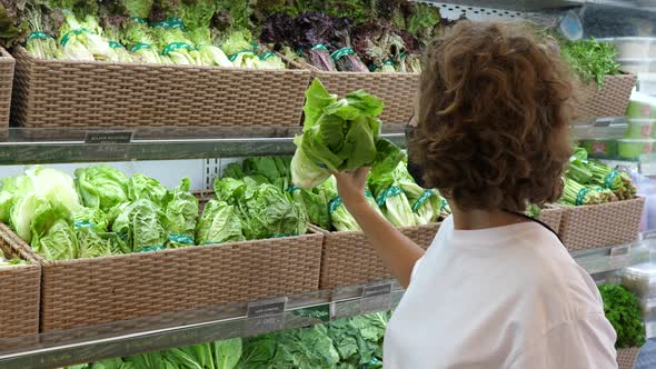 Young Caucasian Woman Wearing a Face Mask Picking Fresh Vegetables in a Supermarket During Covid19