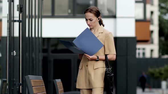 Beautiful professional businesswoman taking out documents from her bag near the office