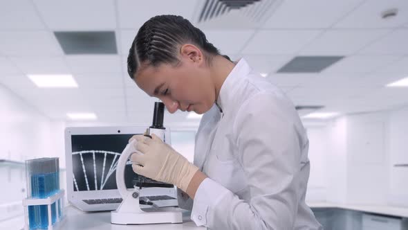 A Female Lab Technician Sitting at a Table Next To a Laptop in a Chemical Laboratory