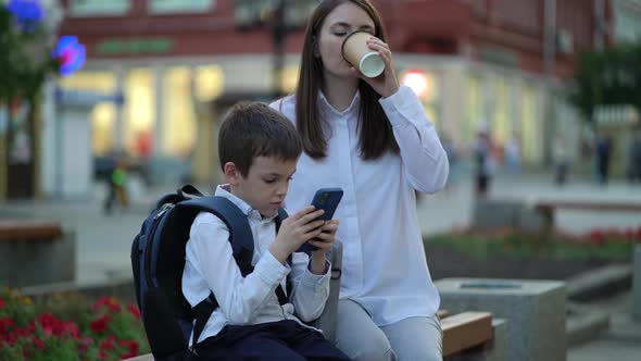 Mom and Son are Sitting on a Bench in the City