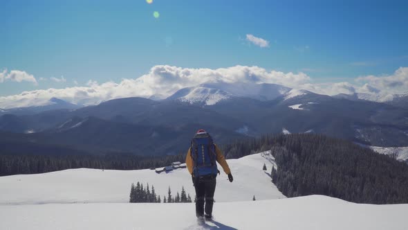 A Man with a Backpack Travels in the Mountains in Winter