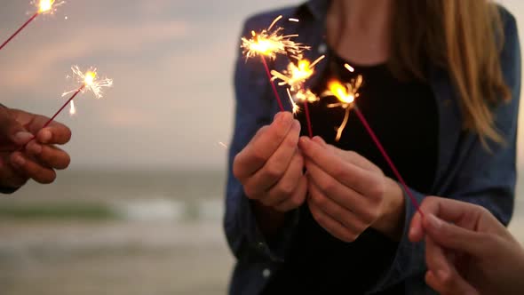 Closeup View of Young People Holding Bengal Lights During Evening Standing By the Sea During Sunset