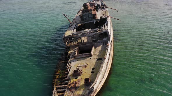 A Wrecked Wooden Ship Lies on the Seashore Covered with Rust