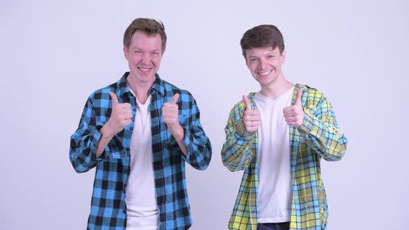 Two Happy Young Handsome Men Giving Thumbs Up Together