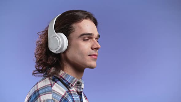 Charming Young Man with Long Hairdo Listening to Music with Wireless Headphones Guy Having Fun