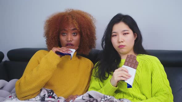 Two Women Lesbian Couple Watching Television and Eating Chocolates