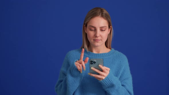 Positive woman wearing blue sweater leafing tape by phone