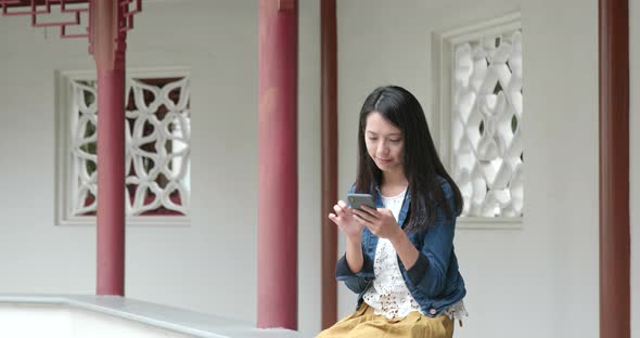 Woman using mobile phone in traditional Chinese garden