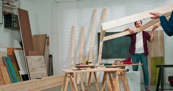 Young Carpenters Build a Solid Wood Wall in a Carpentry Workshop The Carpenters Move the Wall to the