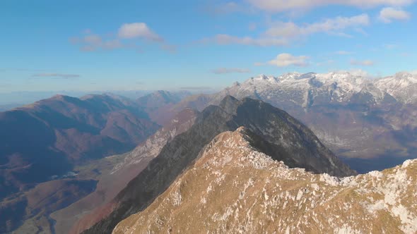 Flying low over mountain ridge revealing top of mountain with three hikers. Drone shot of julian alp