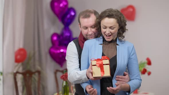 Loving Man Surprising Woman with Gift Box on Valentine's Day