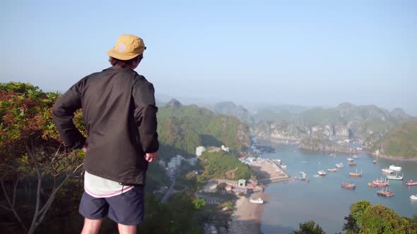 Man Wearing Black Jacket Looking At The View Composed Of Calm Sea and Luxury Yacht In Cat Ba Island