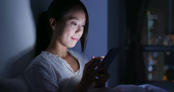 Woman use of mobile phone and lying on bed at night