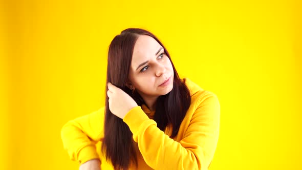 Portrait of Young Woman Combing Her Hair on Yellow Background