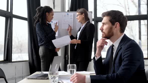 Positive Successful Handsome Business Man in a Formal Suit Sit at Workplace in the Office Looks at