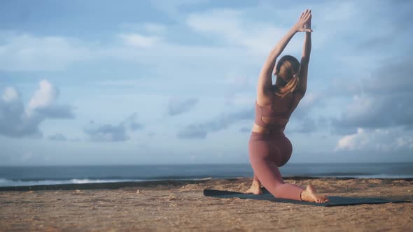 Woman Does Yoga Exercises and Stretches at Morning on Mat at Beach Slow Motion