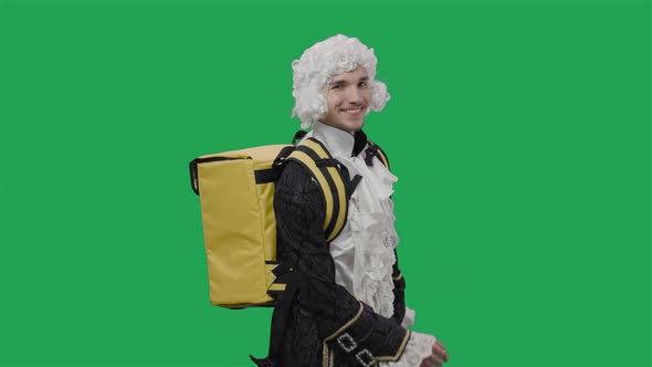 Portrait of Courtier Gentleman in Black Vintage Suit and Wig Walking with Large Yellow Backpack