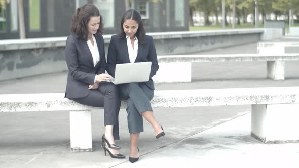 Experienced Businesswomen Sitting Outdoors with Laptop