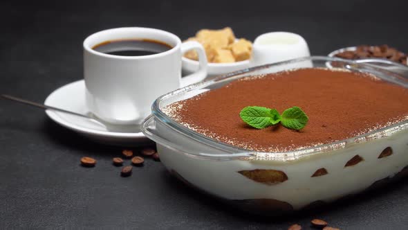 Tiramisu Dessert in Glass Baking Dish and Cup of Espresso Coffee on Concrete Background