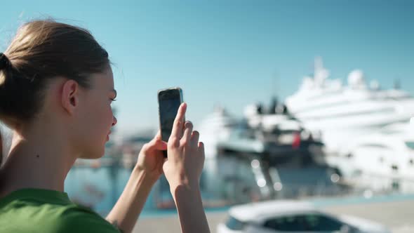 Back view of blonde pensive woman wearing green t-shirt making photo of the seafront