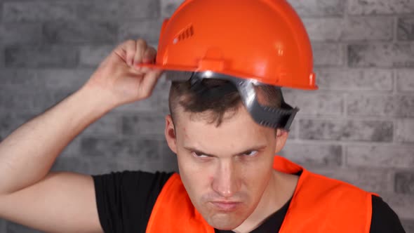 Man in Working Uniform Turning Orange Protective Hardhat