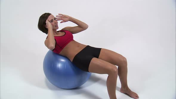 Royalty Free Stock Footage of Woman doing sit-ups on an exercise ball on a white background.