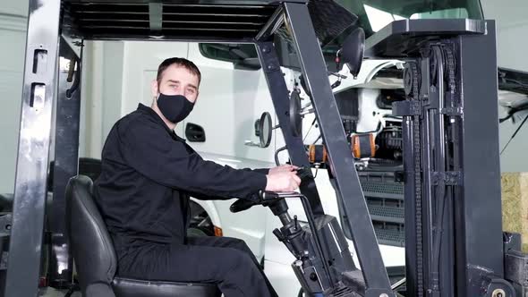 Operator works in protective mask on warehouse loader in repair shop.