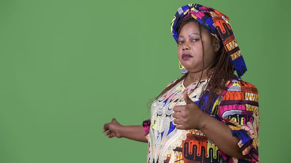 Overweight Beautiful African Woman Wearing Traditional Clothing Against Green Background