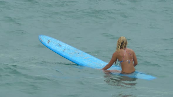 A young woman surfing in a bikini on a longboard surfboard.