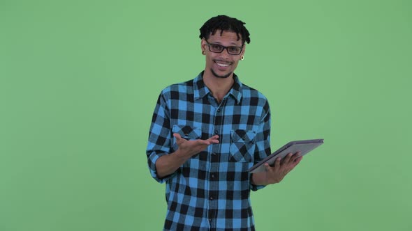 Happy Young African Hipster Man Talking While Using Digital Tablet