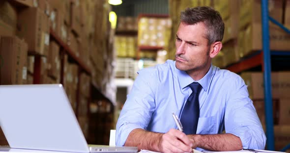 Warehouse Manager Working on Laptop 